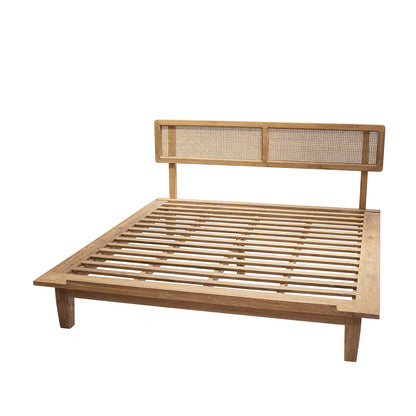 A natural color teak wood bed frame with a rattan headboard.