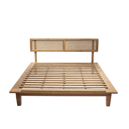 A natural color teak wood bed frame with a rattan headboard.