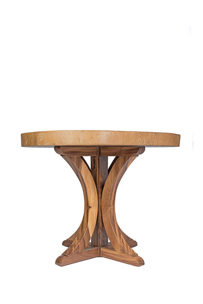 A round dining table made of natural suar wood with a pedestal base, showcasing a rustic design.