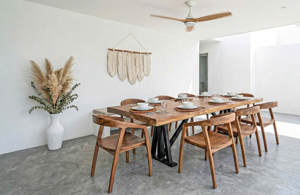 Dining room with wooden table and chairs, pampas grass decor, and concrete flooring.
