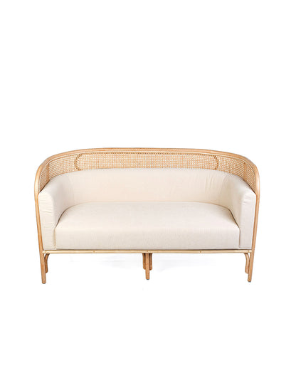 A white textile pillow on a rattan sofa with a natural color frame.