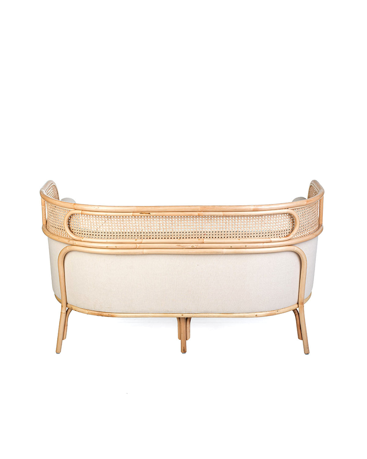 A white textile pillow on a rattan sofa with a natural color frame.