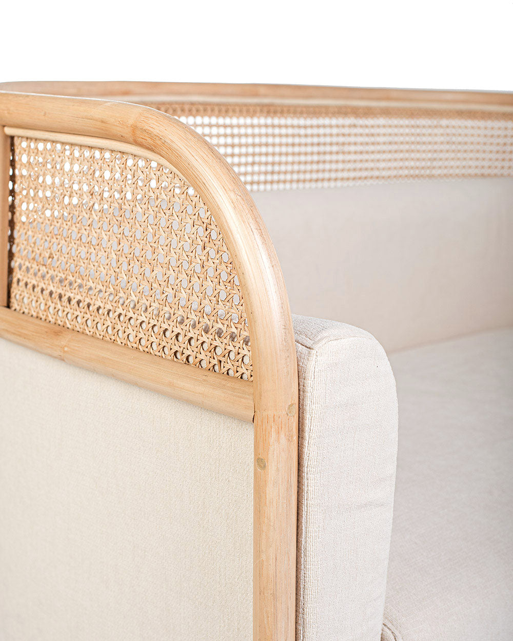 A white textile pillow on a rattan sofa with a natural color frame.