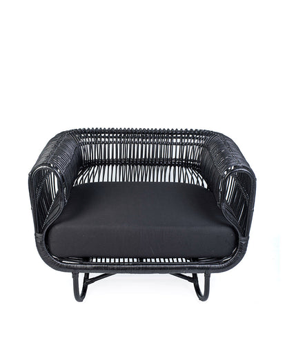 A black rattan solo sofa with a cushion on a white background, showcasing a woven design and a sleek modern look.