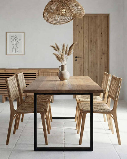 Dining room with wooden table and chairs, vase with pampas grass, and framed artwork on wall.