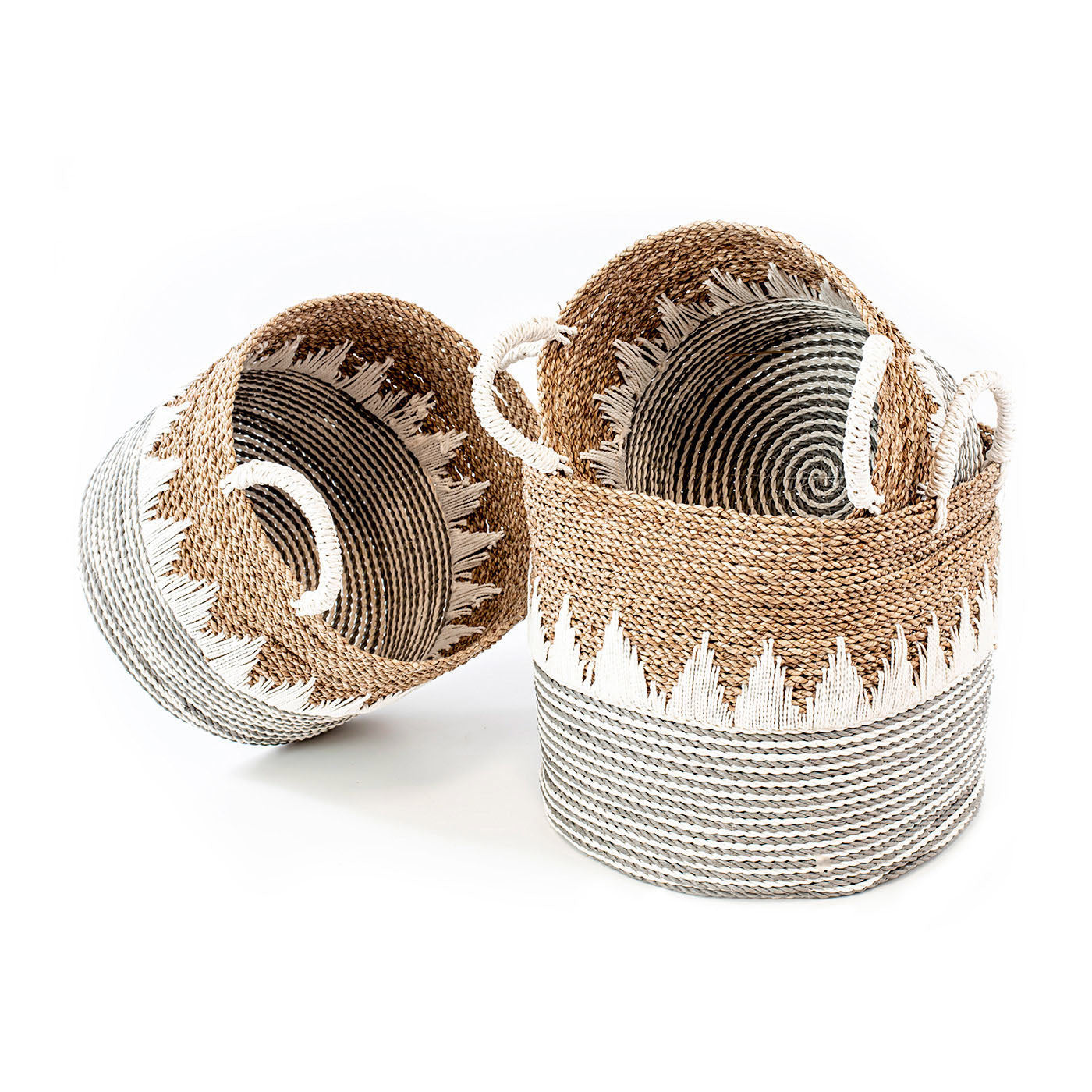 A set of three wicker baskets with natural sea grass color and white macrame accents, with handles on the sides.