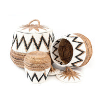 A set of three wicker baskets with geometric patterns, featuring banana leaves and macrame details in natural, white, and black colors.