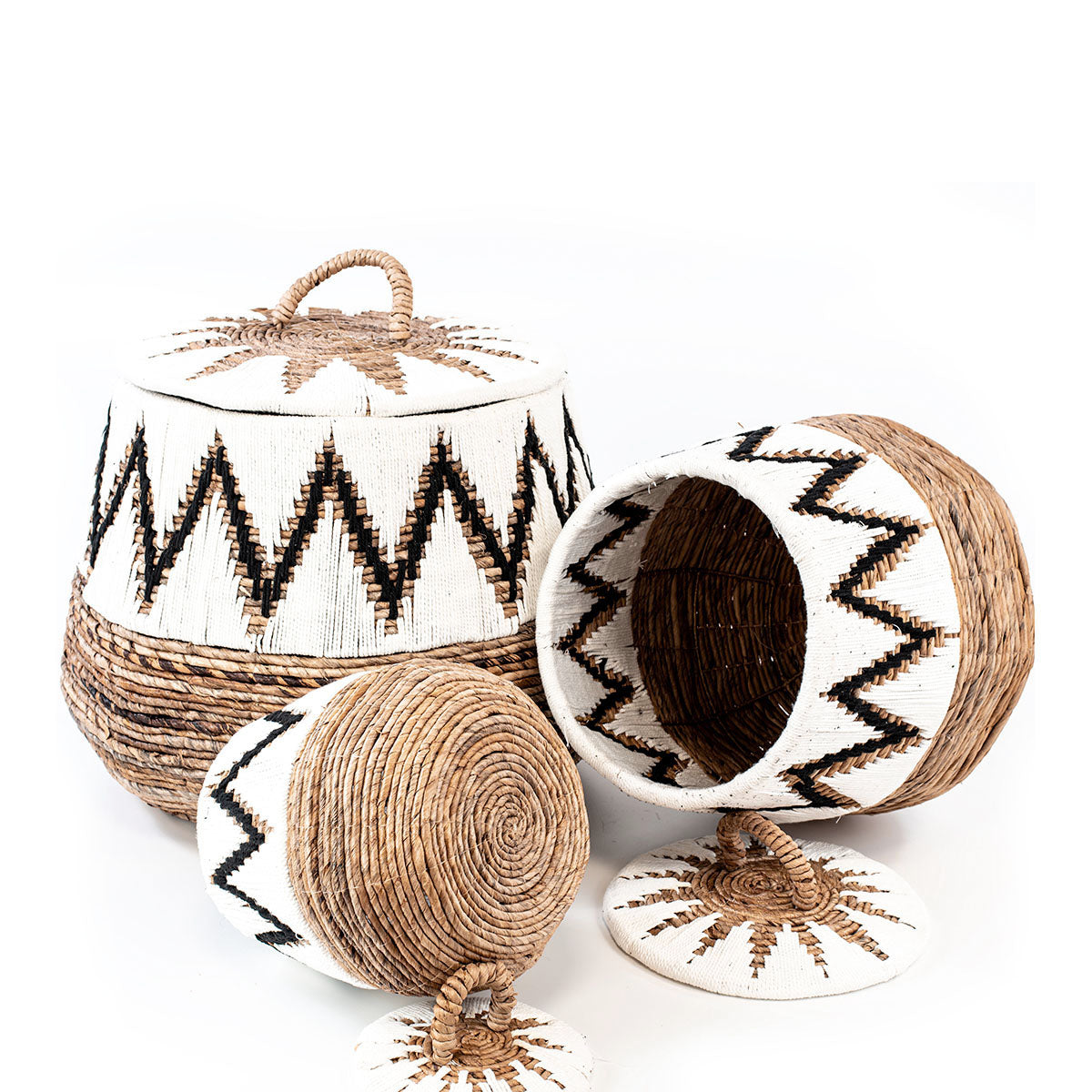 A set of three wicker baskets with geometric patterns, featuring banana leaves and macrame details in natural, white, and black colors.