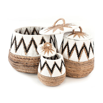 A set of three wicker baskets with geometric patterns, featuring banana leaves and macrame details in natural, white, and black colors.