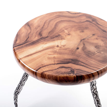 A round teak wood coffee table with a glossy finish and metal support legs with a relief structure. Tabletop view. 