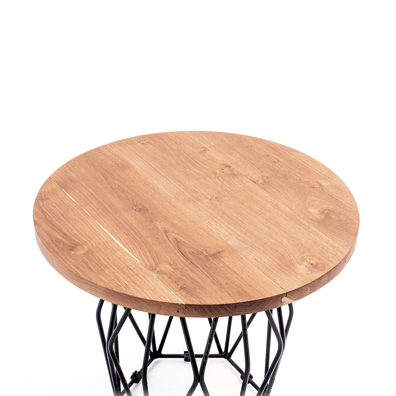 A round suar wood coffee table with a matte finish on a black metal base.