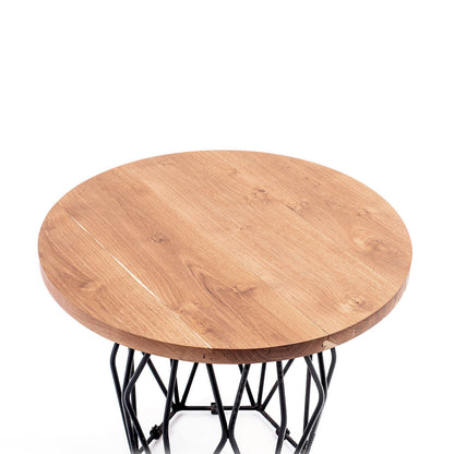 A round suar wood coffee table with a matte finish on a black metal base.