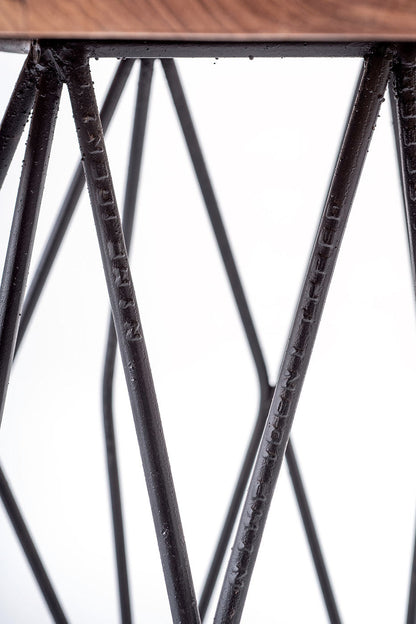 A round suar wood coffee table with a matte finish on a black metal base.