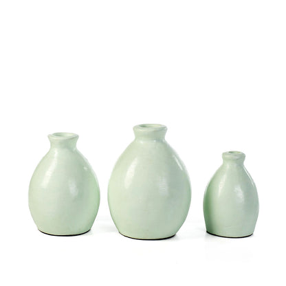 A set of three reseda green ceramic decorative vases with simple shapes on a white background.