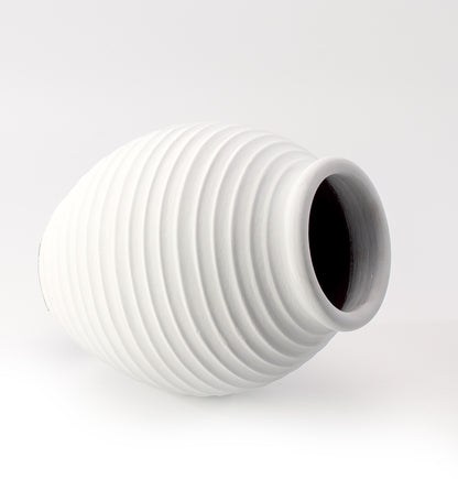A white ceramic decorative vase with a ribbed pattern.