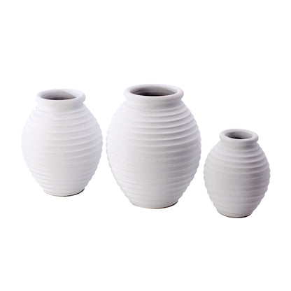 Three white ceramic decorative vases in different sizes with a ribbed pattern.