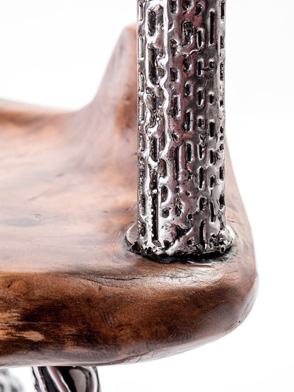 An artistically designed dining chair with a glossy finish on a white background. The chair features a teak wood seat and stainless steel legs with a relief longitudinal structure. Closeup detail. 