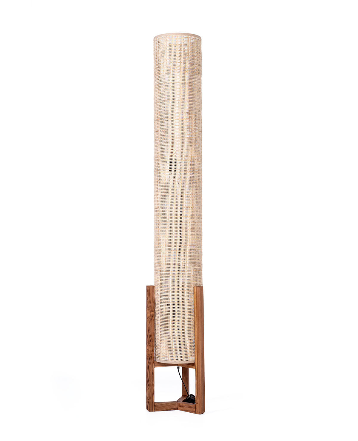 A cylindrical floor lamp with a natural finish teak wood base and an antique rattan shade. The lamp is balanced on a low base and has a slim profile.