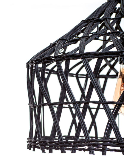 A black pendant lampshade made of rattan, with a rustic design and teak wood accents. A light bulb is visible inside the lampshade.