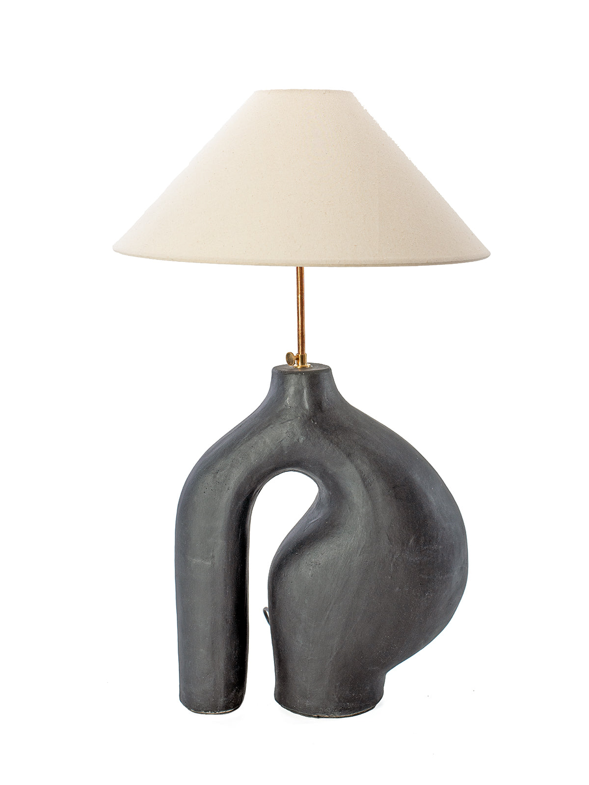 A ceramic base table lamp with an asymmetrical shape and a linen lampshade, in a white background. 