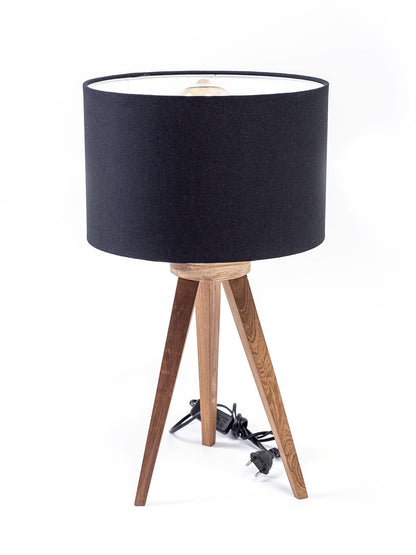 A three-legged table lamp with a black linen shade, teak wood legs.