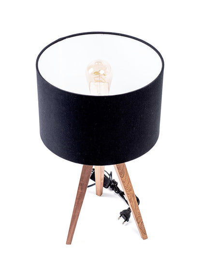 A three-legged table lamp with a black linen shade, teak wood legs.