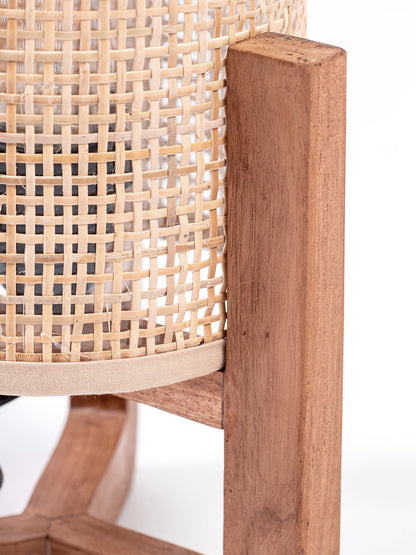 A table lamp with a teak wood base and a cylindrical antique rattan shade, with a visible power cable.