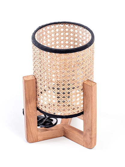 A table lamp with a teak wood base and a cylindrical antique rattan shade, with a visible power cable.