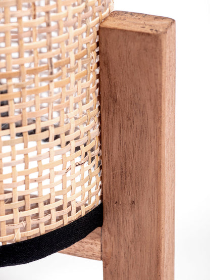 A table lamp with a teak wood base and a cylindrical antique rattan shade, with a visible power cable.