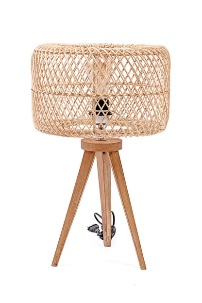 A three-legged table lamp with a teak wood base and a rattan shade, in natural color. The lamp is switched off and placed against a white background.