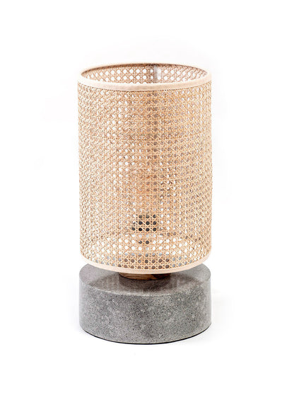 A table lamp with a rattan shade and a grey terrazzo base, standing on a flat surface.