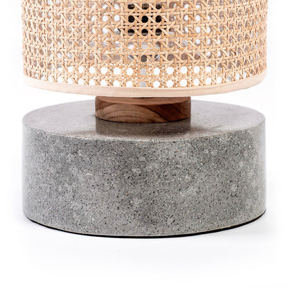 A table lamp with a rattan shade and a grey terrazzo base, standing on a flat surface.