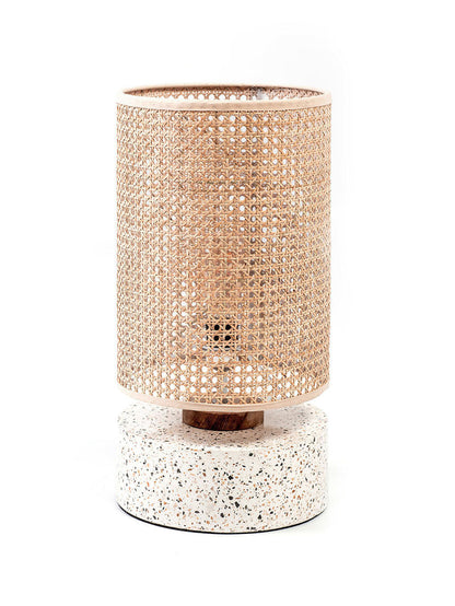 A table lamp with a white terrazzo base and a cylindrical rattan shade, suitable for a living room or bedroom setting.